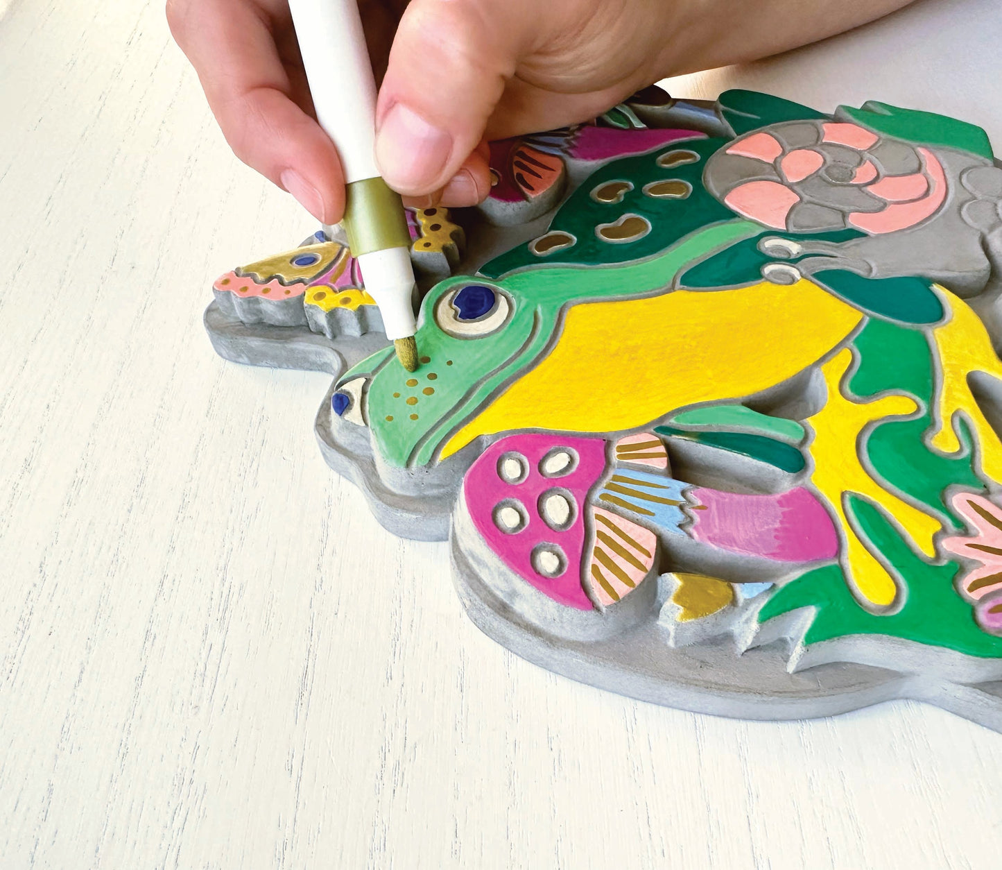 A person using a marker to color the garden stone on a white background.