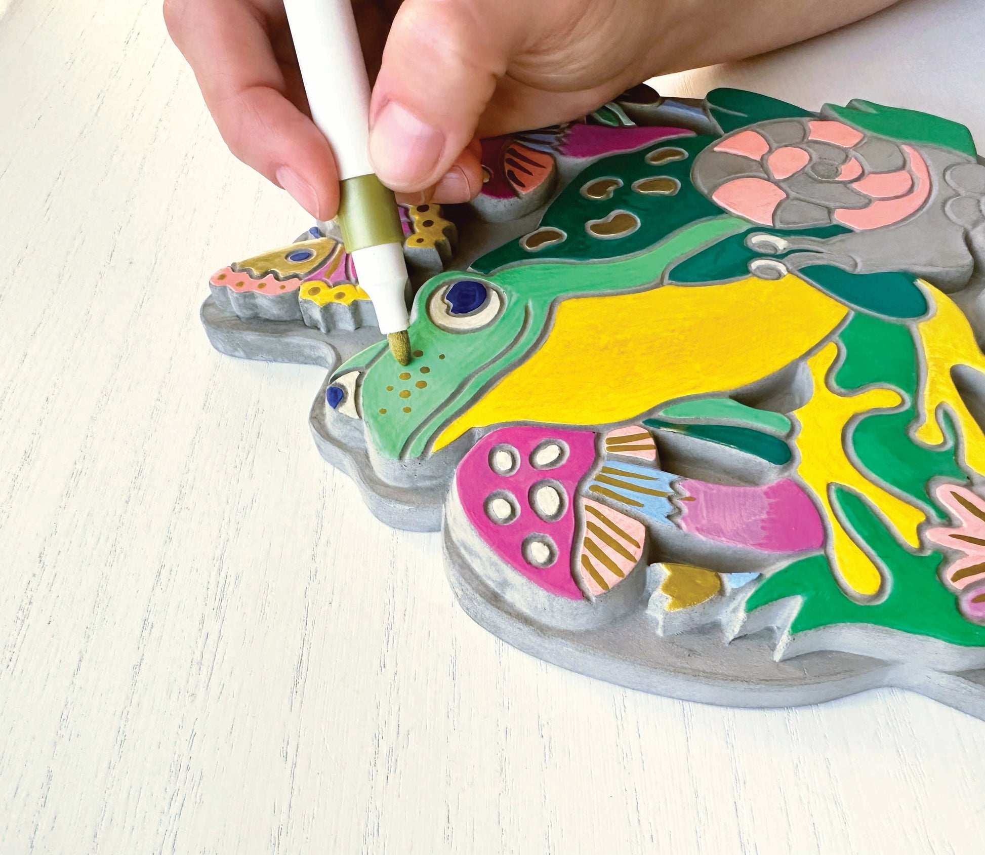A person using a marker to color the garden stone on a white background.